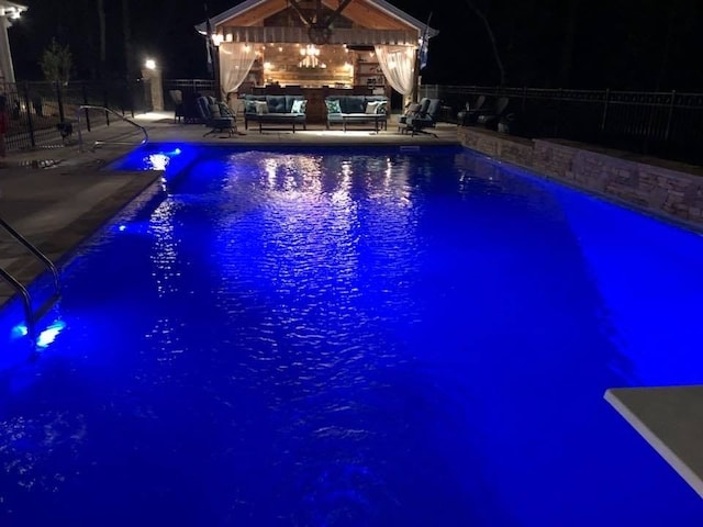 pool at twilight with a fireplace and a patio area