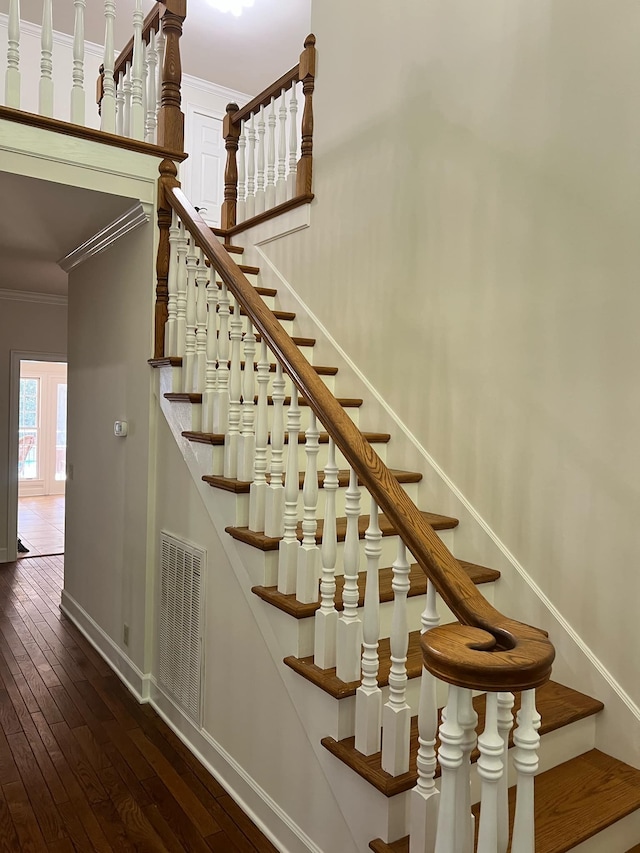 staircase with wood-type flooring and ornamental molding