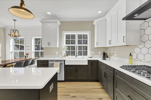 kitchen featuring white cabinets, sink, light hardwood / wood-style flooring, wall chimney range hood, and stainless steel appliances