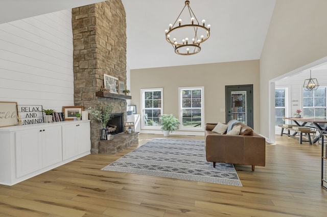 living room with a stone fireplace, light hardwood / wood-style flooring, wood walls, and high vaulted ceiling