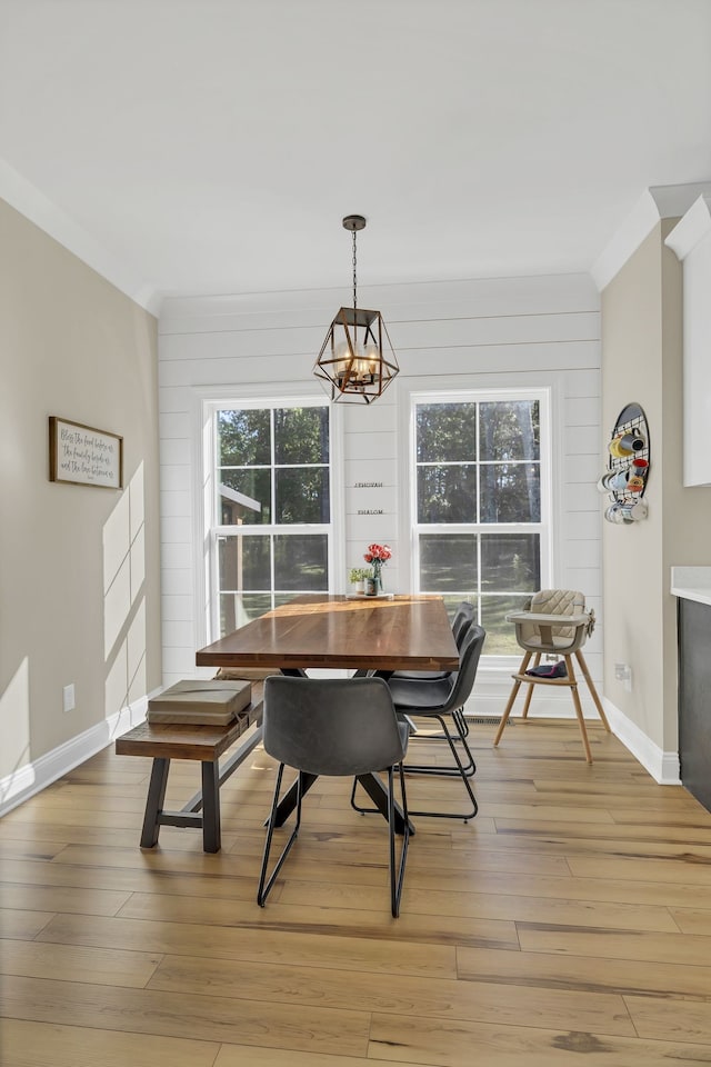 dining room featuring light wood-type flooring, wood walls, and an inviting chandelier