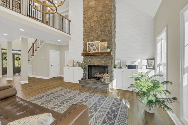 living room with hardwood / wood-style flooring, high vaulted ceiling, and a stone fireplace