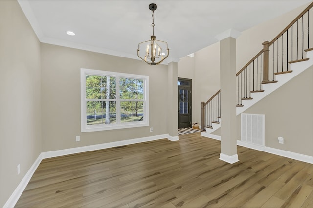 foyer entrance featuring ornamental molding, hardwood / wood-style floors, and an inviting chandelier