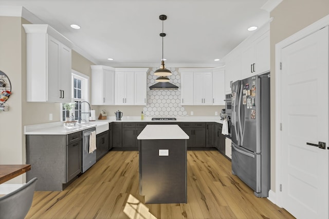 kitchen with gray cabinets, light wood-type flooring, a kitchen island, decorative light fixtures, and stainless steel appliances