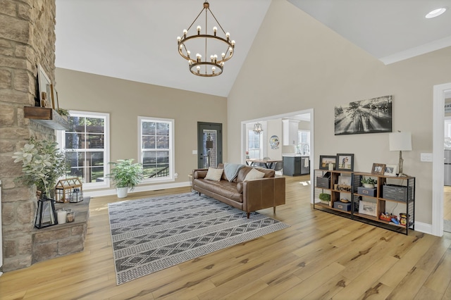 living room with ornate columns, light wood-type flooring, high vaulted ceiling, and a chandelier