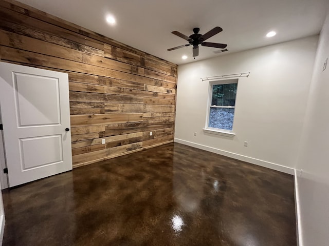 spare room featuring wood walls and ceiling fan