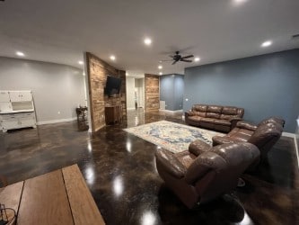 home theater featuring concrete floors, a stone fireplace, and ceiling fan