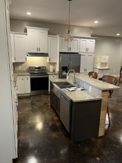 kitchen with white cabinets, appliances with stainless steel finishes, hanging light fixtures, and sink