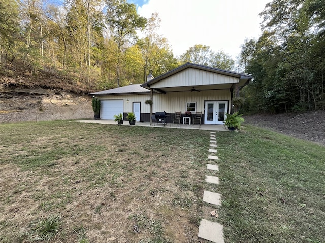 view of front of home featuring a garage, a front lawn, ceiling fan, and french doors