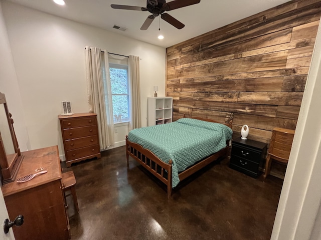 bedroom with ceiling fan and wood walls