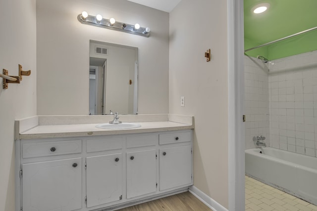 bathroom featuring hardwood / wood-style flooring, vanity, and tiled shower / bath combo