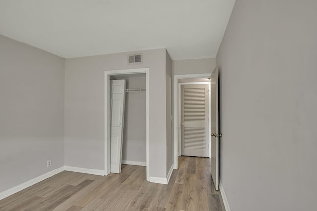 unfurnished bedroom with a closet and light hardwood / wood-style floors