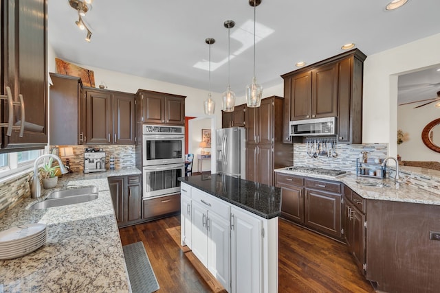 kitchen featuring decorative light fixtures, appliances with stainless steel finishes, dark wood-type flooring, and sink