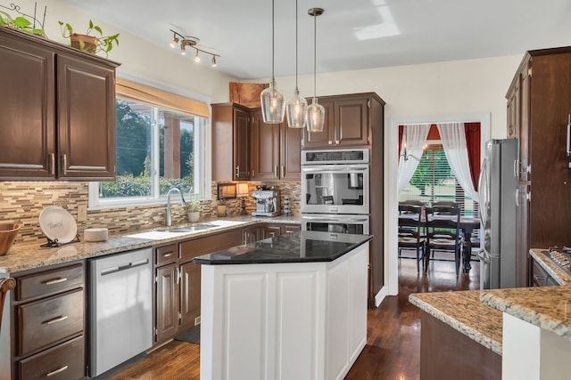 kitchen featuring appliances with stainless steel finishes, tasteful backsplash, pendant lighting, dark hardwood / wood-style floors, and sink