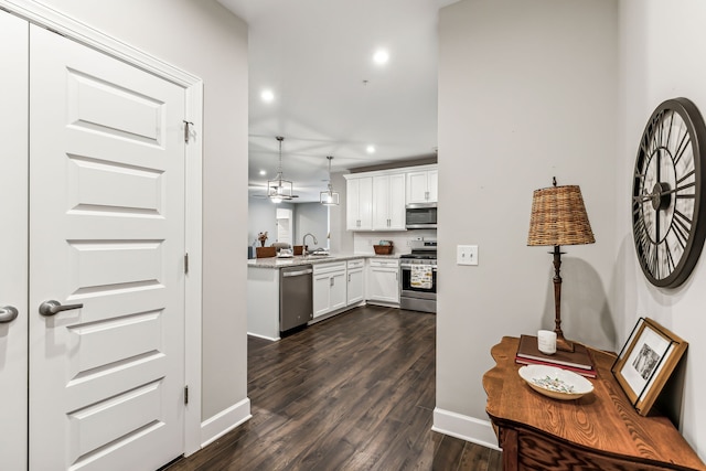 kitchen with pendant lighting, dark wood-type flooring, sink, white cabinets, and stainless steel appliances