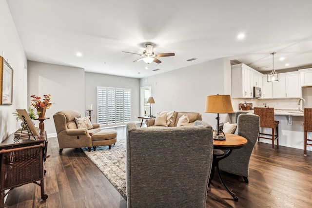 living room with ceiling fan, dark hardwood / wood-style floors, and sink