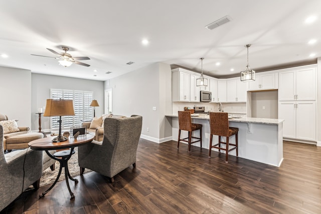 living room featuring ceiling fan and dark hardwood / wood-style flooring