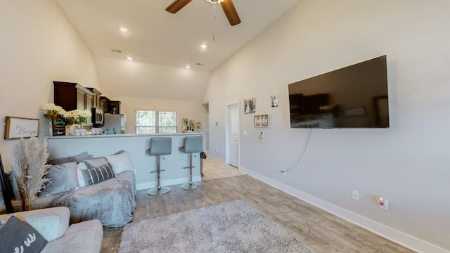 living room with ceiling fan, light hardwood / wood-style floors, and high vaulted ceiling