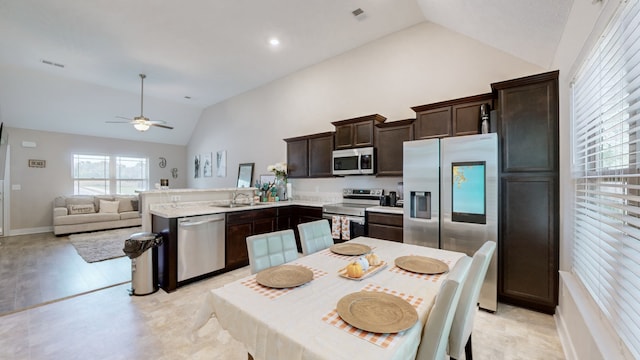 kitchen with ceiling fan, sink, dark brown cabinets, appliances with stainless steel finishes, and vaulted ceiling