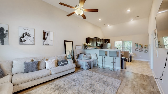 living room featuring light wood-type flooring, ceiling fan, and high vaulted ceiling