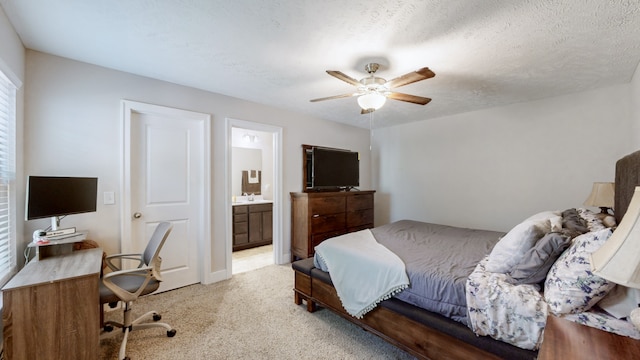 bedroom featuring ceiling fan, light colored carpet, a textured ceiling, and connected bathroom