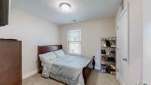 bedroom with light carpet and a textured ceiling