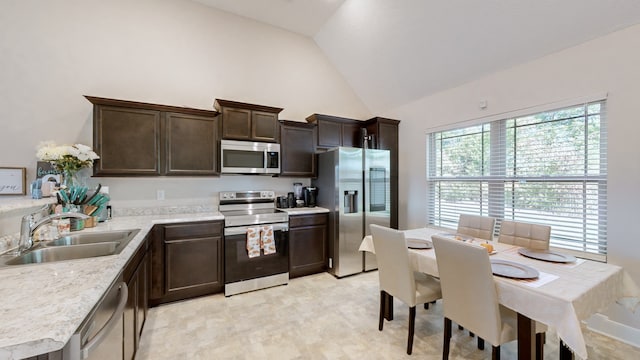 kitchen featuring dark brown cabinetry, stainless steel appliances, sink, and lofted ceiling