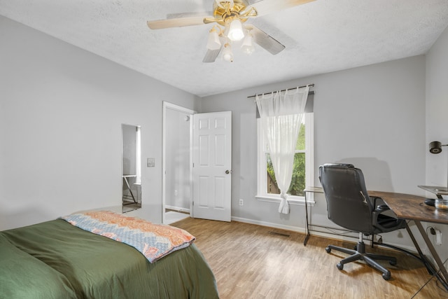 bedroom with a textured ceiling, wood-type flooring, and ceiling fan