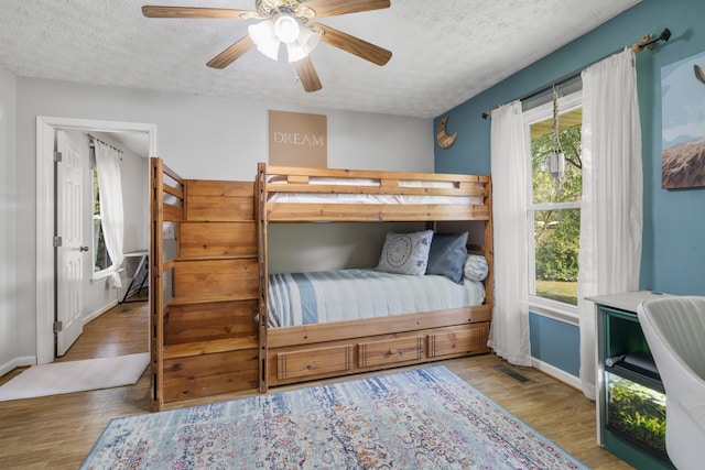 bedroom featuring ceiling fan, hardwood / wood-style flooring, and a textured ceiling