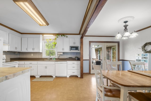 kitchen with pendant lighting, white cabinets, white appliances, and a healthy amount of sunlight