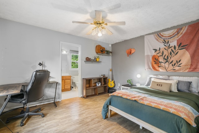 bedroom featuring light wood-type flooring, ensuite bath, ceiling fan, and a textured ceiling