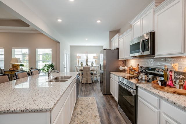 kitchen featuring a kitchen island with sink, white cabinets, dark hardwood / wood-style floors, a kitchen bar, and stainless steel appliances