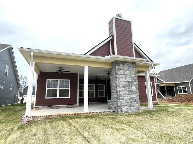 rear view of property with a lawn and ceiling fan