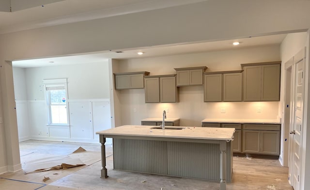 kitchen featuring sink, light hardwood / wood-style flooring, an island with sink, gray cabinets, and a breakfast bar