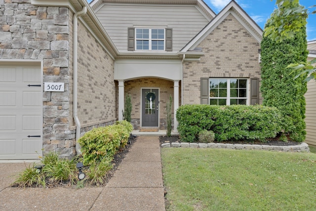 view of exterior entry with a garage and a yard