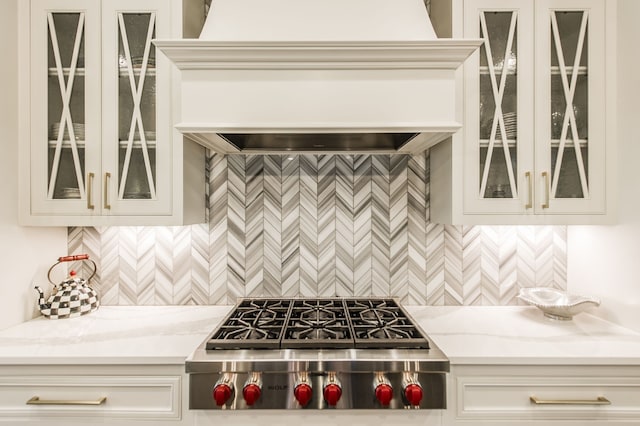 kitchen featuring backsplash, stainless steel gas cooktop, light stone countertops, and custom exhaust hood