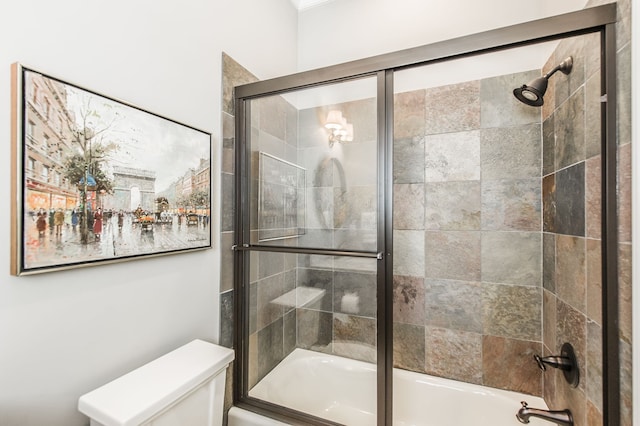 bathroom with shower / bath combination with glass door and toilet