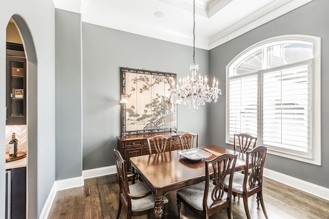 dining area featuring ornamental molding, a notable chandelier, and dark hardwood / wood-style flooring