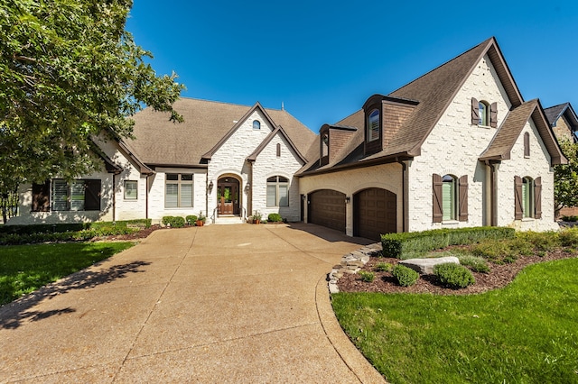 french country home featuring a garage and a front lawn