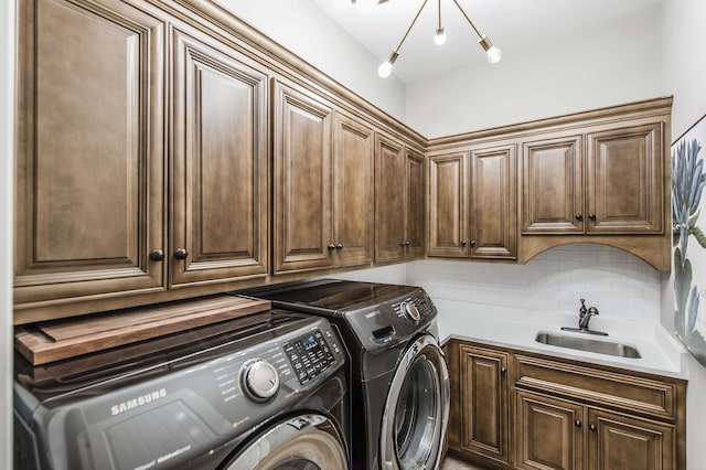 washroom featuring a chandelier, sink, washer and dryer, and cabinets