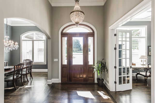 foyer featuring a notable chandelier, crown molding, dark wood-type flooring, and a healthy amount of sunlight