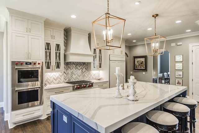 kitchen with a large island, appliances with stainless steel finishes, decorative light fixtures, and custom exhaust hood