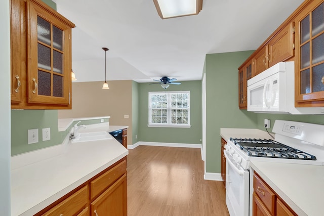 kitchen with white appliances, sink, hanging light fixtures, ceiling fan, and light wood-type flooring