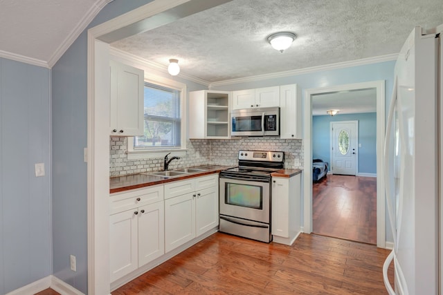 kitchen featuring appliances with stainless steel finishes, white cabinetry, butcher block counters, light hardwood / wood-style flooring, and sink