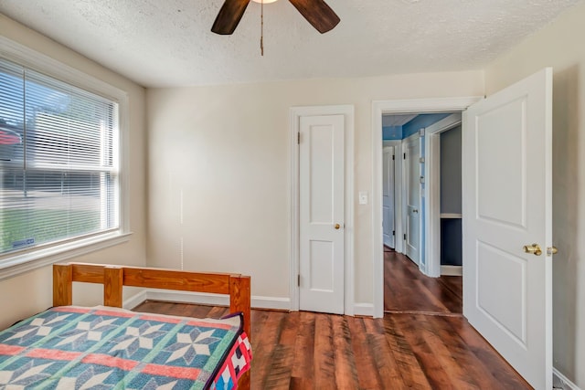 bedroom with a textured ceiling, ceiling fan, and dark hardwood / wood-style flooring