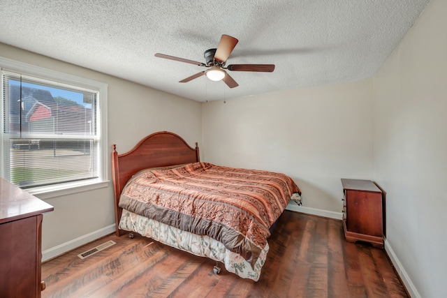 bedroom with ceiling fan, a textured ceiling, and dark wood-type flooring