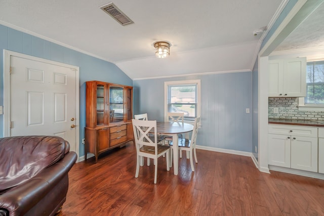 dining space featuring crown molding, wood walls, vaulted ceiling, and dark hardwood / wood-style flooring