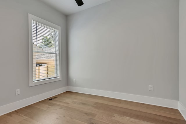 empty room featuring a wealth of natural light, ceiling fan, and light wood-type flooring