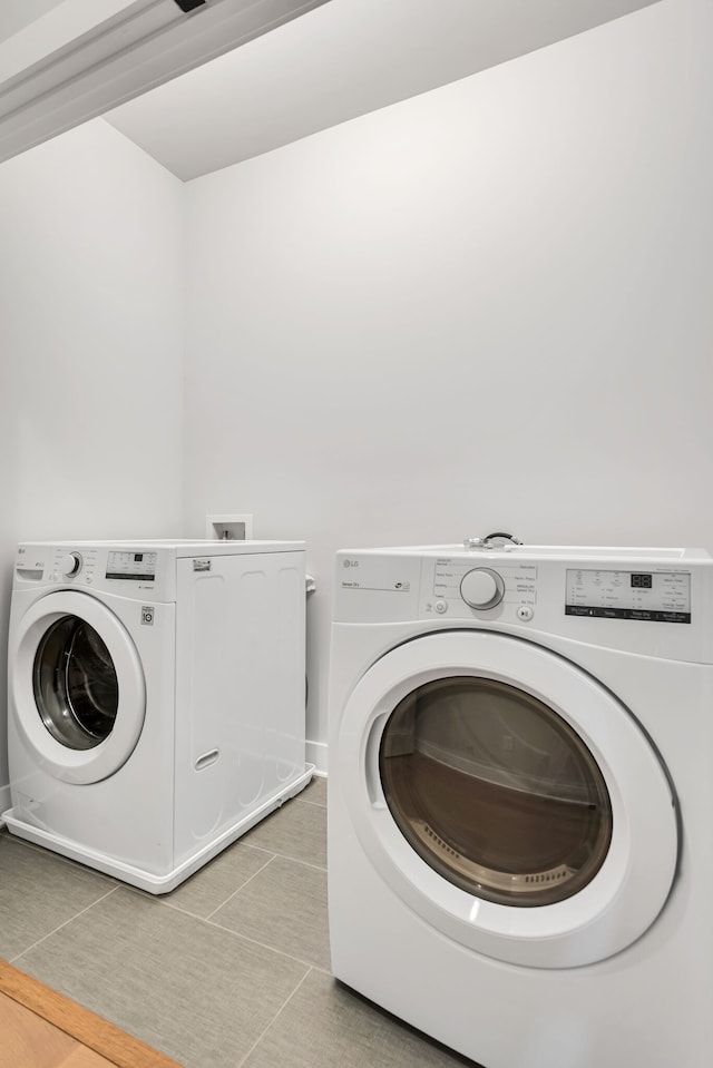 clothes washing area featuring washer and clothes dryer and tile patterned flooring