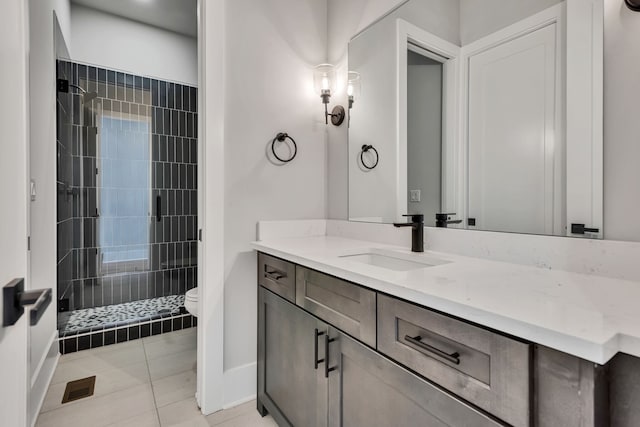 bathroom with tiled shower, tile patterned flooring, vanity, and toilet